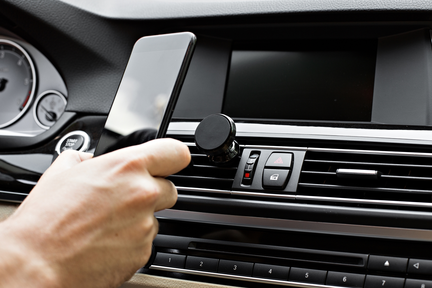 Persona poniendo un móvil en un soporte magnético situado en las rejillas de ventilación de un vehículo
